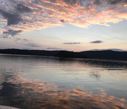 A serene lake at sunset, with colorful clouds reflecting on the water and hills in the background.