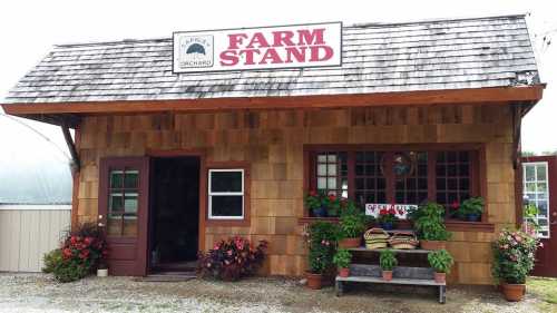 A charming farm stand with a wooden exterior, flower pots, and a sign reading "Farm Stand" above the entrance.