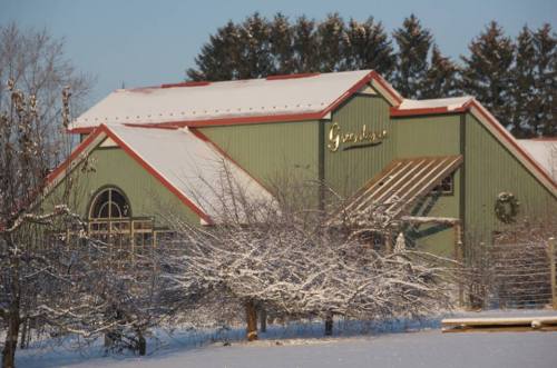 A green barn with a red roof, surrounded by snow-covered trees and a winter landscape.