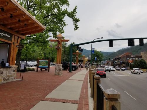 A scenic street view with shops, traffic lights, and trees lining the road in a small town.