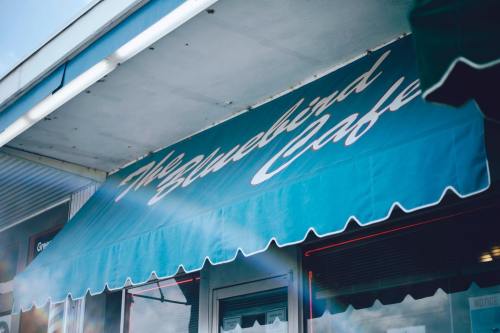 A teal awning with the text "The Bluebird Cafe" in white cursive lettering.
