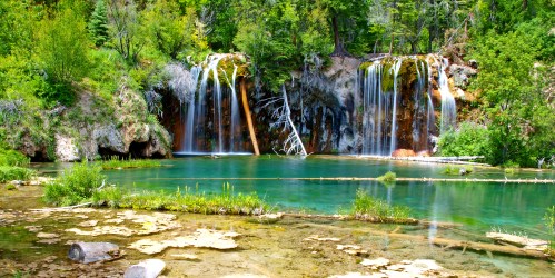 A serene landscape featuring cascading waterfalls surrounded by lush greenery and a tranquil blue pool.