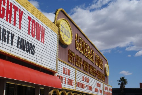 A colorful marquee sign for a theater, featuring bright letters and a blue sky with clouds in the background.