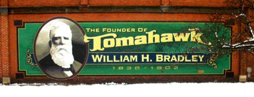 A mural featuring a portrait of William H. Bradley, founder of Tomahawk, with text and a snowy background.