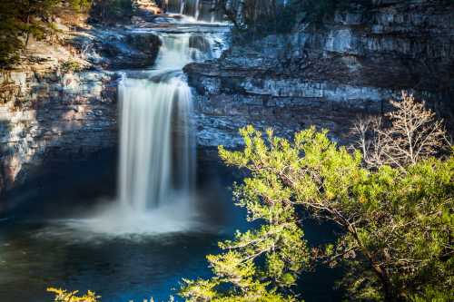 A serene waterfall cascades over rocky cliffs, surrounded by lush greenery and a tranquil pool below.