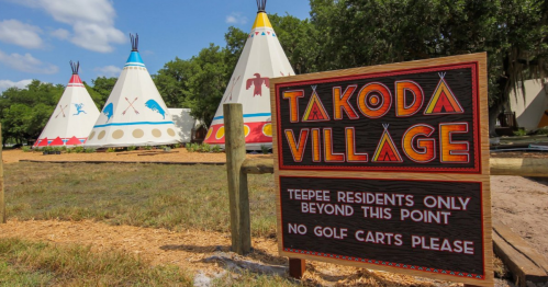 Sign for Takoda Village with colorful teepees in the background, stating "Teepee residents only beyond this point."