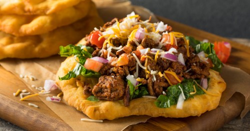 Homemade Indian fry bread tacos loaded with meat, cheese, and toppings.