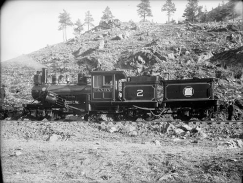 A vintage steam locomotive numbered 2, set against a rocky landscape with sparse trees.