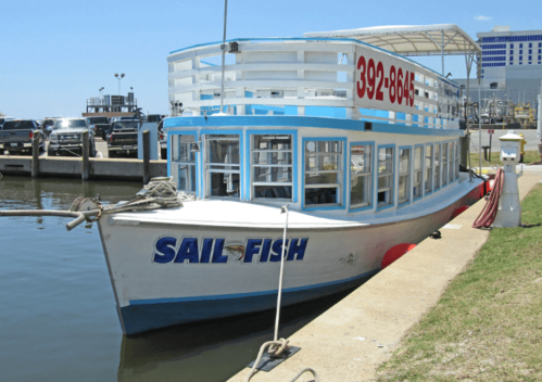A white boat named "Sail Fish" docked at a marina on a sunny day.