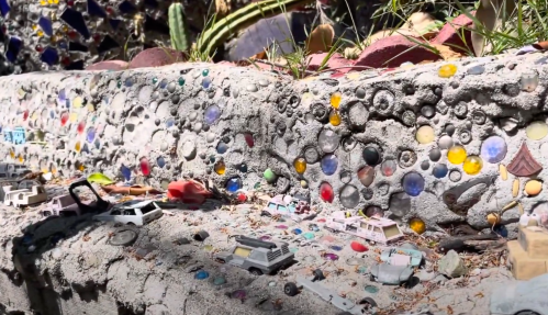 A textured concrete surface adorned with colorful stones and small toy cars scattered across it.