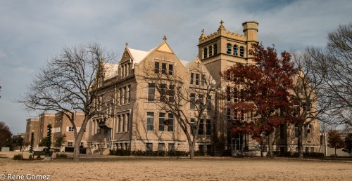 Historic building with ornate architecture, surrounded by bare trees and a clear sky.