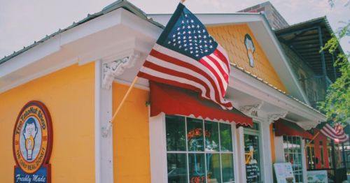 A colorful building with an American flag, featuring a sign that says "Freshly Made" and decorative elements.