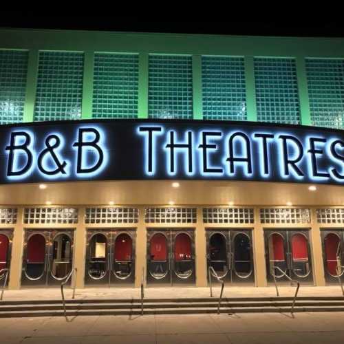 Exterior of B&B Theatres at night, featuring a bright marquee and glass block windows.