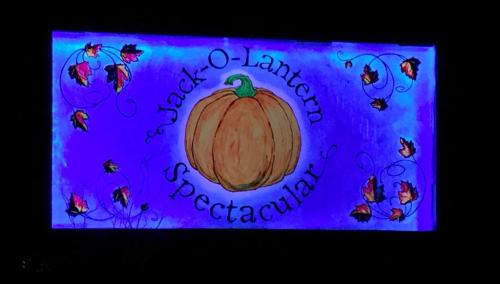 A colorful sign featuring a pumpkin and autumn leaves, reading "Jack-O-Lantern Spectacular."
