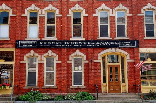 Historic brick building with large windows and a sign for Robert H. Newell & Co., a shirt manufacturing company.