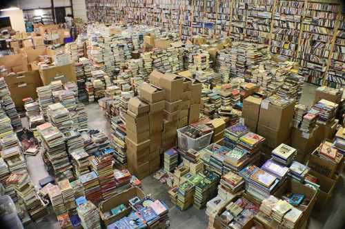 A large warehouse filled with stacks of books and boxes, creating a chaotic yet vibrant book collection.