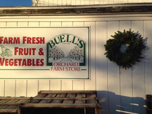 Sign for Buell's Orchard Farm Store featuring "Farm Fresh Fruit & Vegetables" and a decorative wreath on the wall.