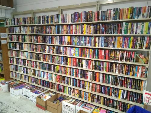 A large bookshelf filled with various books, with boxes of books stacked below.