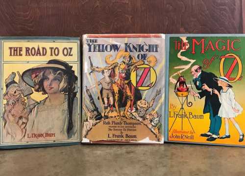 Three vintage books: "The Road to Oz," "The Yellow Knight of Oz," and "The Magic of Oz," featuring colorful covers.