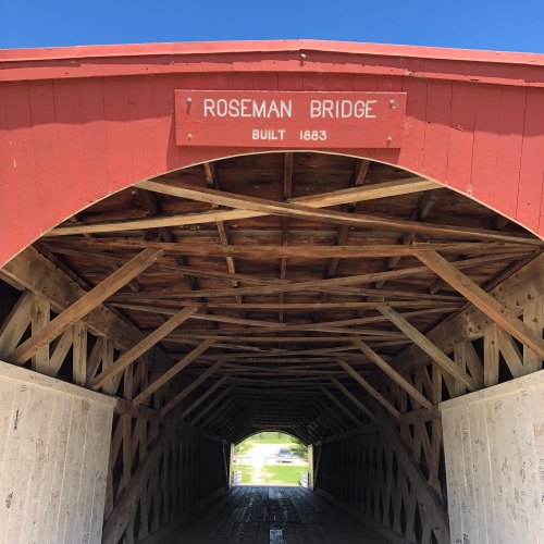 View of the interior of Roseman Bridge, a red covered bridge with a sign indicating it was built in 1863.