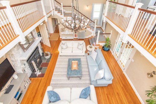 Spacious living room with high ceilings, a chandelier, and cozy seating around a coffee table on a patterned rug.