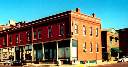 Historic brick building with large windows, featuring a sign that reads "Ohio Block," set against a clear blue sky.