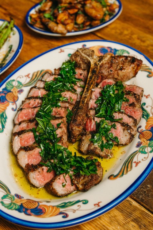 A beautifully plated steak, sliced and garnished with fresh herbs, served on a decorative dish.