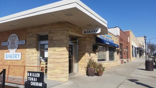 A bakery with a stone exterior and a sign reading "Dutch Oven Bakery" on a sunny street with shops nearby.