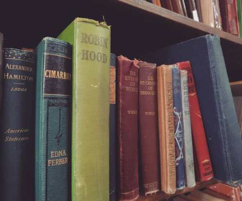 A close-up of a bookshelf filled with various vintage books in different colors and sizes.