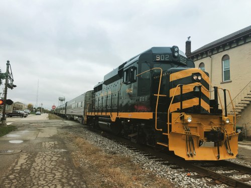 A vintage black and yellow train engine parked beside a building on a cloudy day.