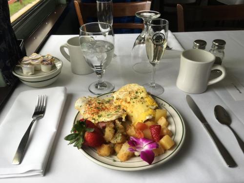 A plate of eggs with fruit, toast, and a flower, set on a table with glasses of water and coffee.