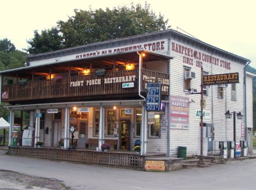 A rustic two-story building with a restaurant and store, featuring a porch and various signs, set in a rural area.