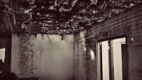 Abandoned room with damaged ceiling, exposed insulation, and an exit door on the right.