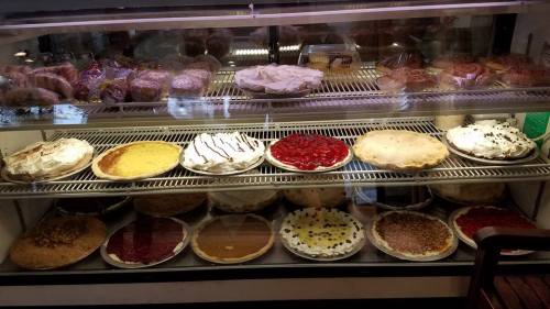 A display case filled with various pies, including fruit, cream, and nut varieties, all beautifully arranged.