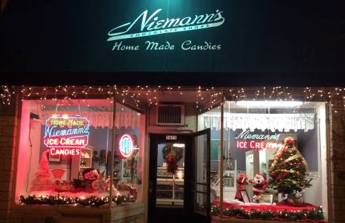 A festive storefront with holiday decorations, featuring "Niemann's Homemade Candies" and a Christmas tree in the window.