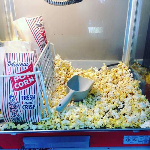 A popcorn machine with bags of popcorn and scattered popcorn kernels on the counter.