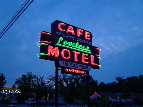 Neon sign for Loveless Cafe and Motel, featuring bright colors and retro design against a twilight sky.