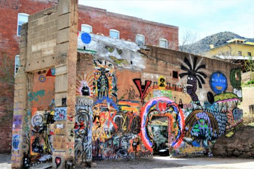 Colorful graffiti covers a weathered wall, featuring various artistic designs and vibrant patterns in an urban setting.