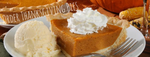A slice of pumpkin pie topped with whipped cream, served with a scoop of ice cream on a plate.