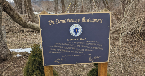 A plaque from the Commonwealth of Massachusetts honoring Thomas E. Reed, set in a natural outdoor area.