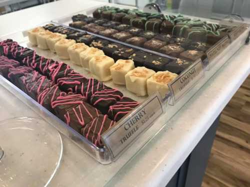 A display of assorted chocolates, including cherry, coconut, and mint varieties, arranged in a clear tray.