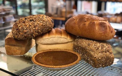 A variety of freshly baked breads and a pie on a display counter in a bakery.