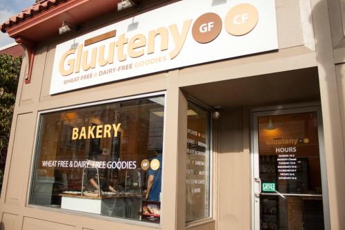 Exterior of a bakery named "Glutteny," featuring a sign for wheat-free and dairy-free goodies.