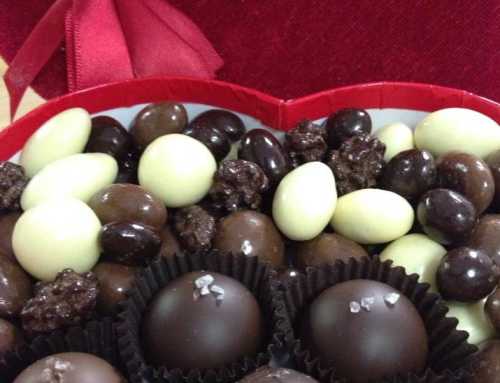 A heart-shaped box filled with assorted chocolates, including dark, milk, and white varieties.