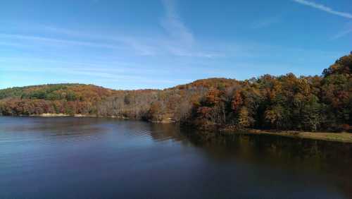 A serene lake surrounded by autumn-colored trees under a clear blue sky.