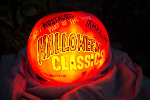 A carved pumpkin glowing with the text "Halloween Classics" and other decorative phrases on its surface.