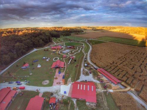 Aerial view of a rural landscape featuring a park with play areas, paths, and fields under a cloudy sky.