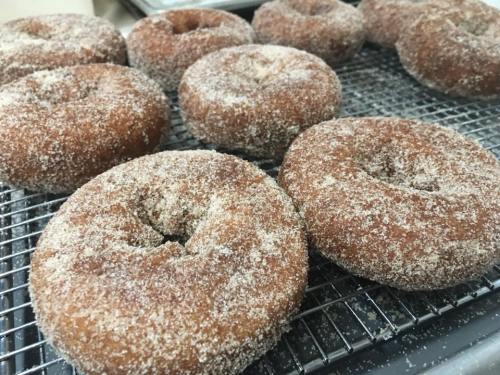 A close-up of freshly made donuts coated in sugar, resting on a wire rack.