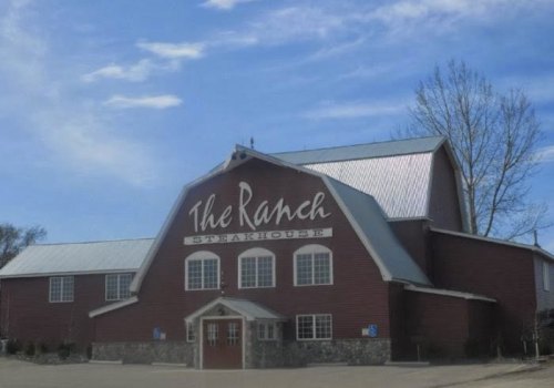 Red barn-style building with "The Ranch Steakhouse" sign, featuring a metal roof and large windows.