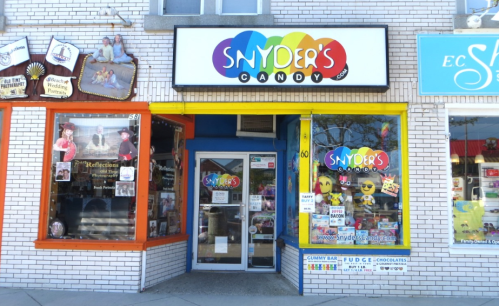 Colorful storefront of Snyder's Candy, featuring a bright sign and large windows displaying various candy items.